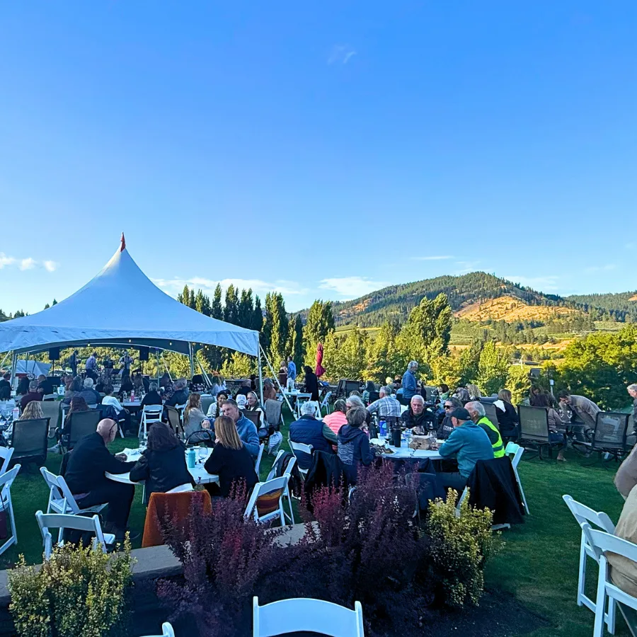 Guests seated on the lawn at Silvara Cellars for an outdoor event, with a tent and valley view in the background