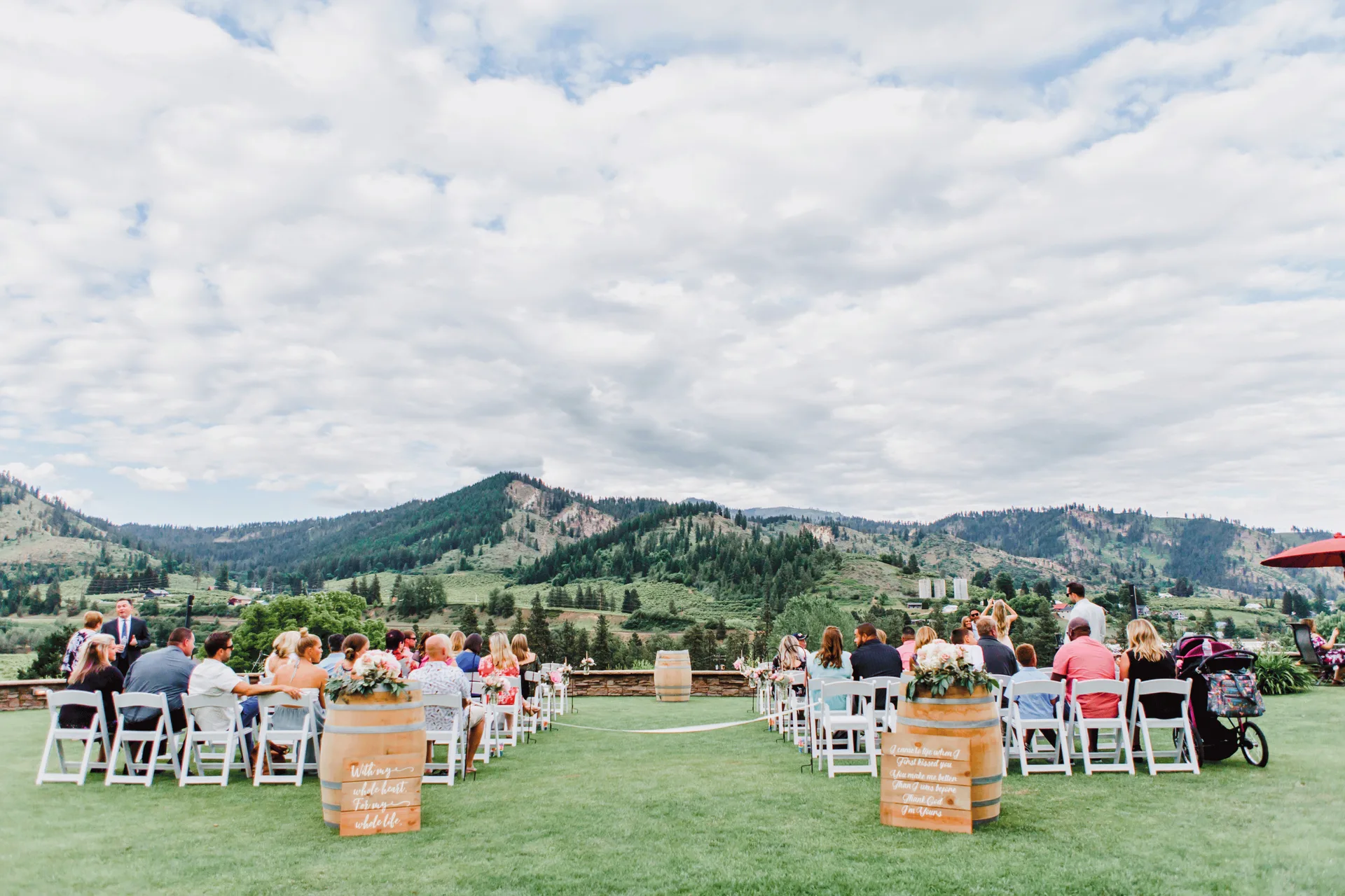 Guests seated either side of a barrel-lined aisle on the lawn at Silvara Cellars, facing the mountains across the valley