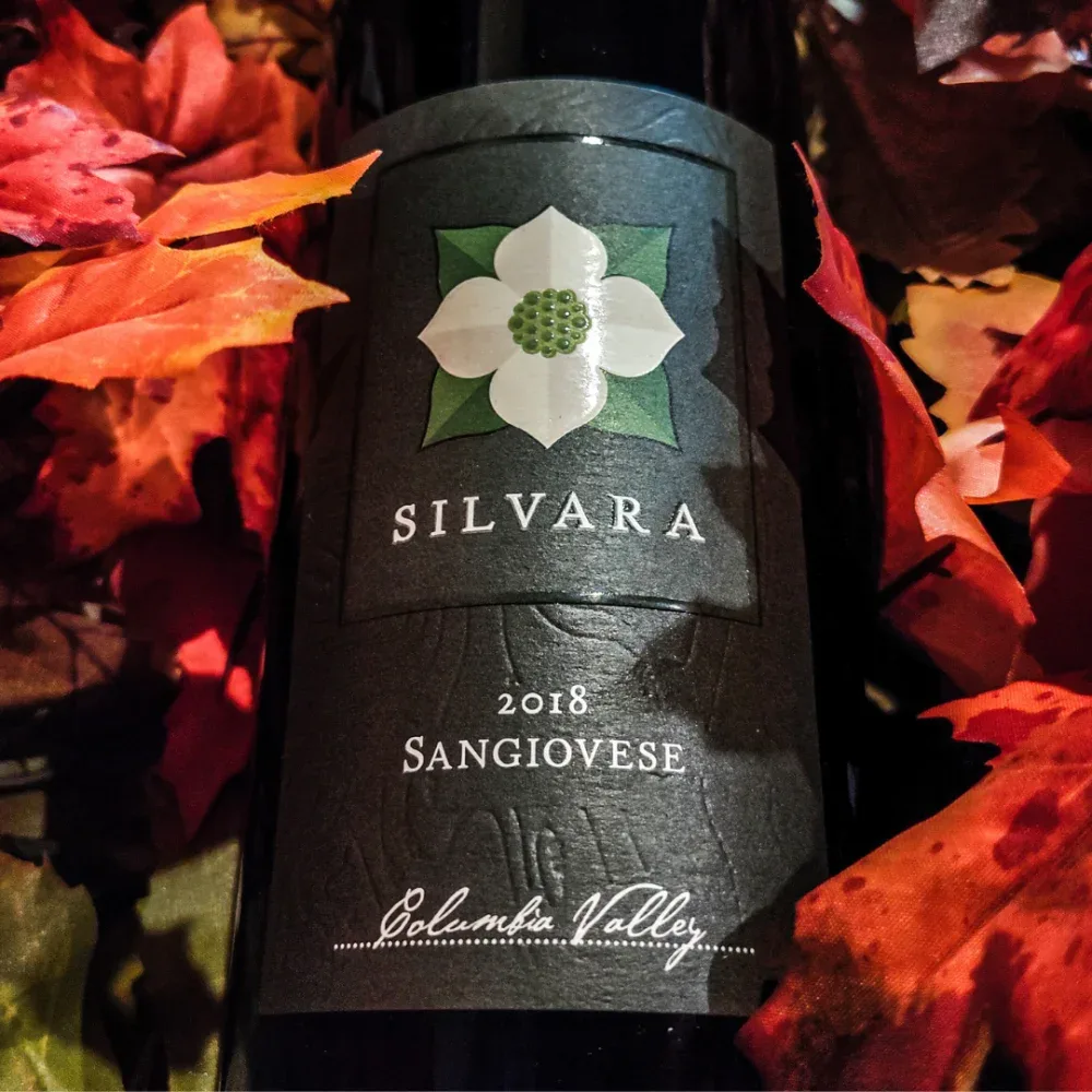 Close-up of a Silvara 2018 Sangiovese wine bottle surrounded by autumn leaves.